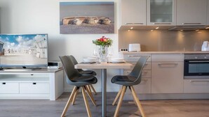 Et moderne køkken med spisebord, stole og en vase med blomster.
