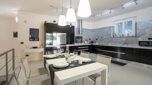 Een moderne keuken met zwart-wit keukenkastjes, roestvrijstalen apparatuur en hanglampen.