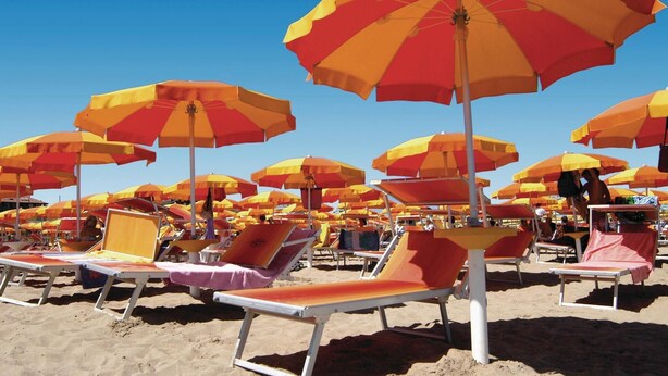 Een strand met veel parasols en ligbedden.