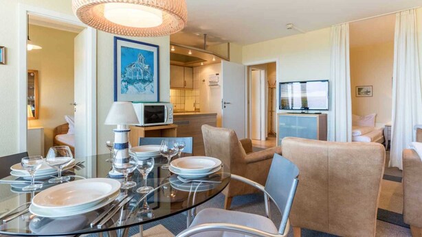 A modern hotel room with a dining area, kitchenette, and a large window. - Apartment 187 (ID 093) (Sankt Peter-Ording)