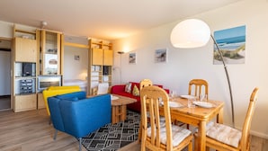 A compact living space with a kitchenette, a dining area, and a seating area with a sofa and chairs.