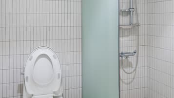 A modern bathroom with a toilet, a glass shower enclosure, and tiled walls.