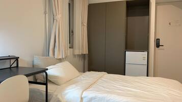 Et hotelværelse med seng, skrivebord, stol, garderobeskab og minibar.