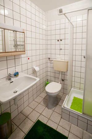 A bathroom with a white sink, toilet, and shower.