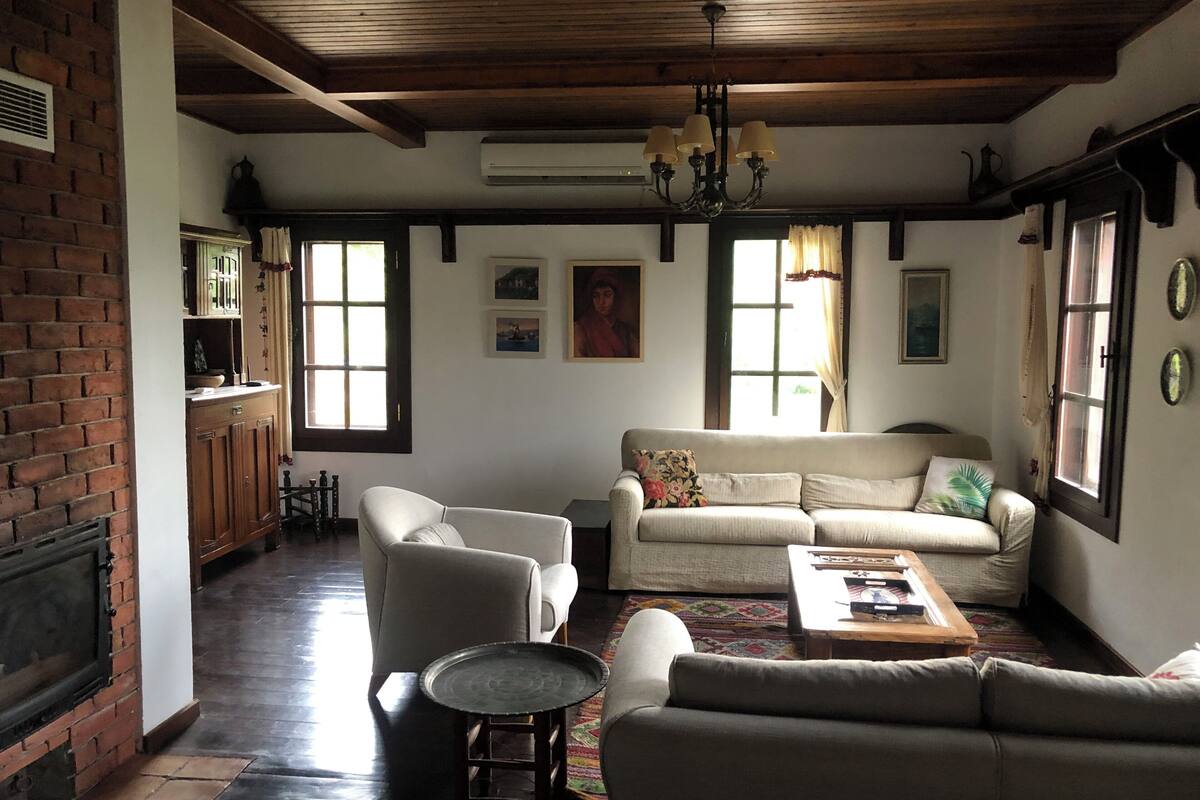 Un salon comprenant un canapé, des fauteuils, une table basse, un lustre et une cheminée.