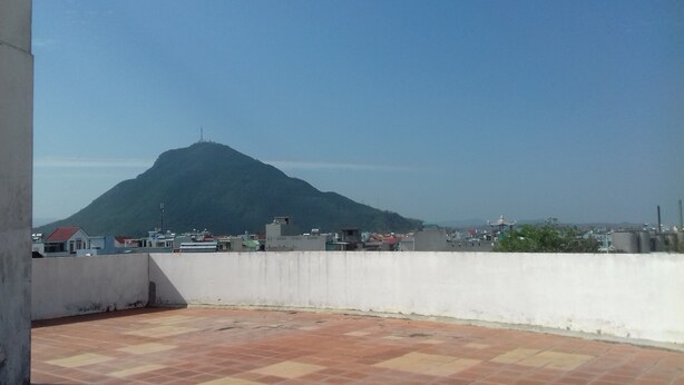 Terraza en la azotea con vistas a una montaña y edificios circundantes.