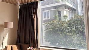A modern room with a large window, a sofa, a lamp, and a ceiling with wooden paneling.