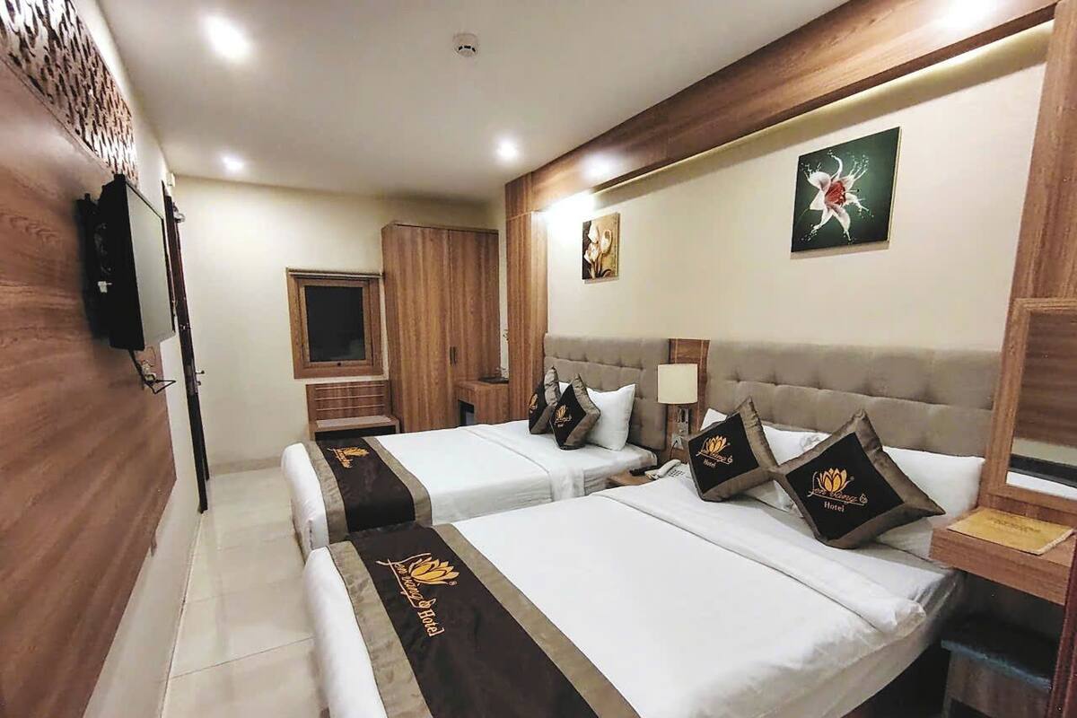 Een hotelkamer met twee bedden, houten lambrisering, een televisie en kunstwerken aan de muur.