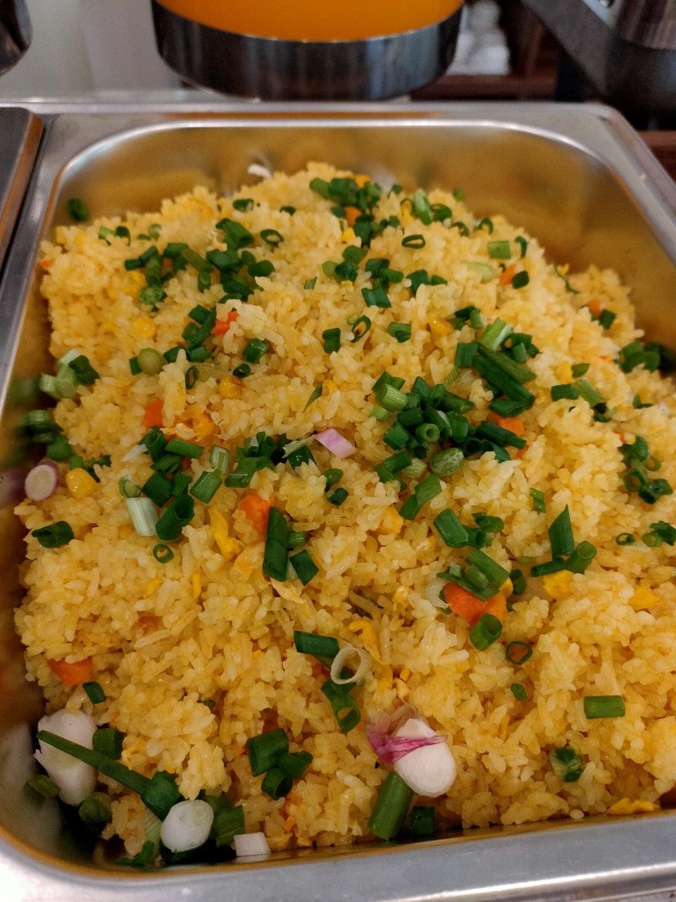 A tray of fried rice garnished with green onions and diced vegetables.