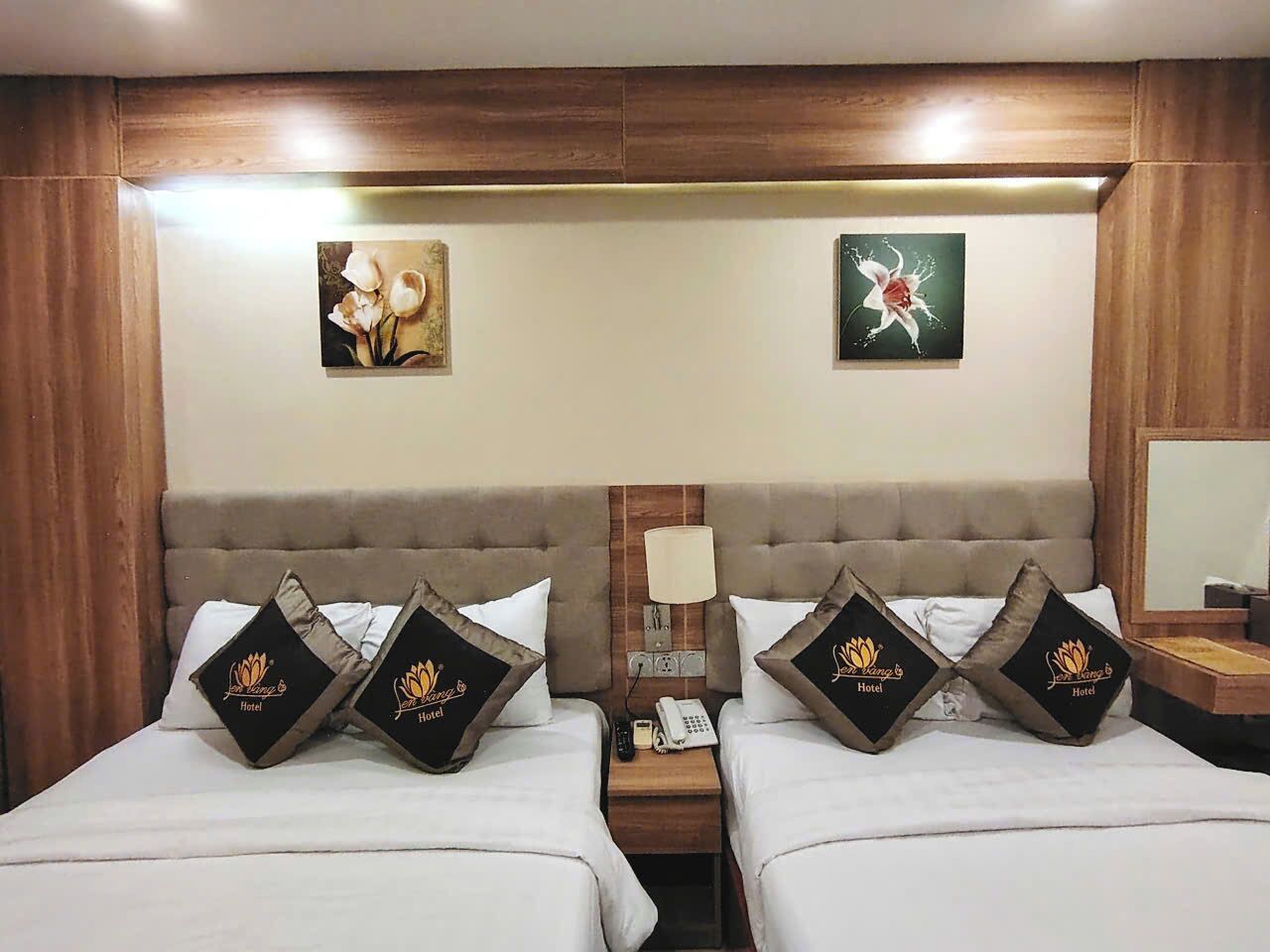 Habitación de hotel con dos camas, cada una con almohadas a juego y una mesita de noche con lámpara y teléfono.