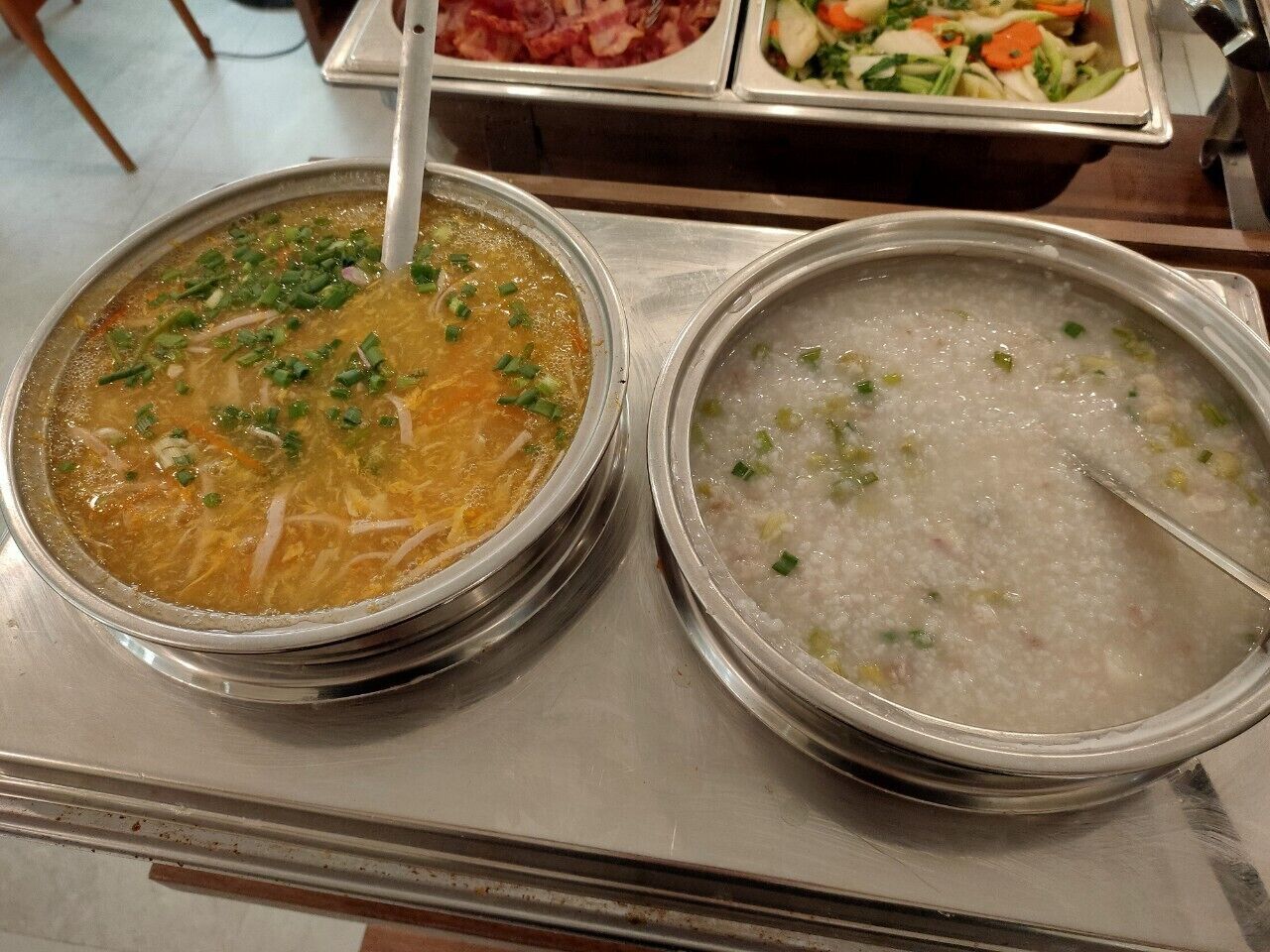 Two bowls of soup on a stainless steel table.