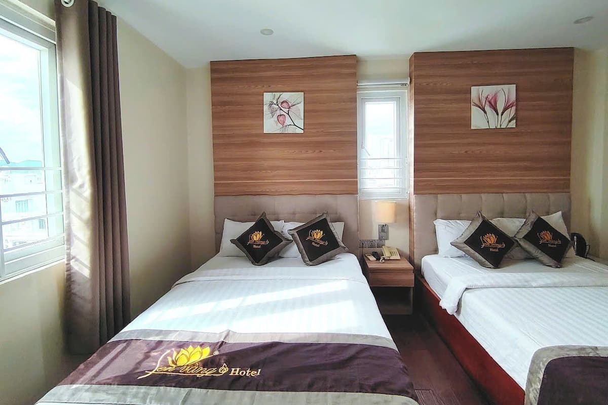 Een hotelkamer met twee bedden, houten hoofdborden en kunstwerken aan de muur.