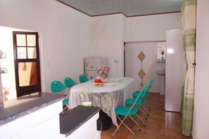 A compact kitchen with a dining table, chairs, a refrigerator, and a sink.
