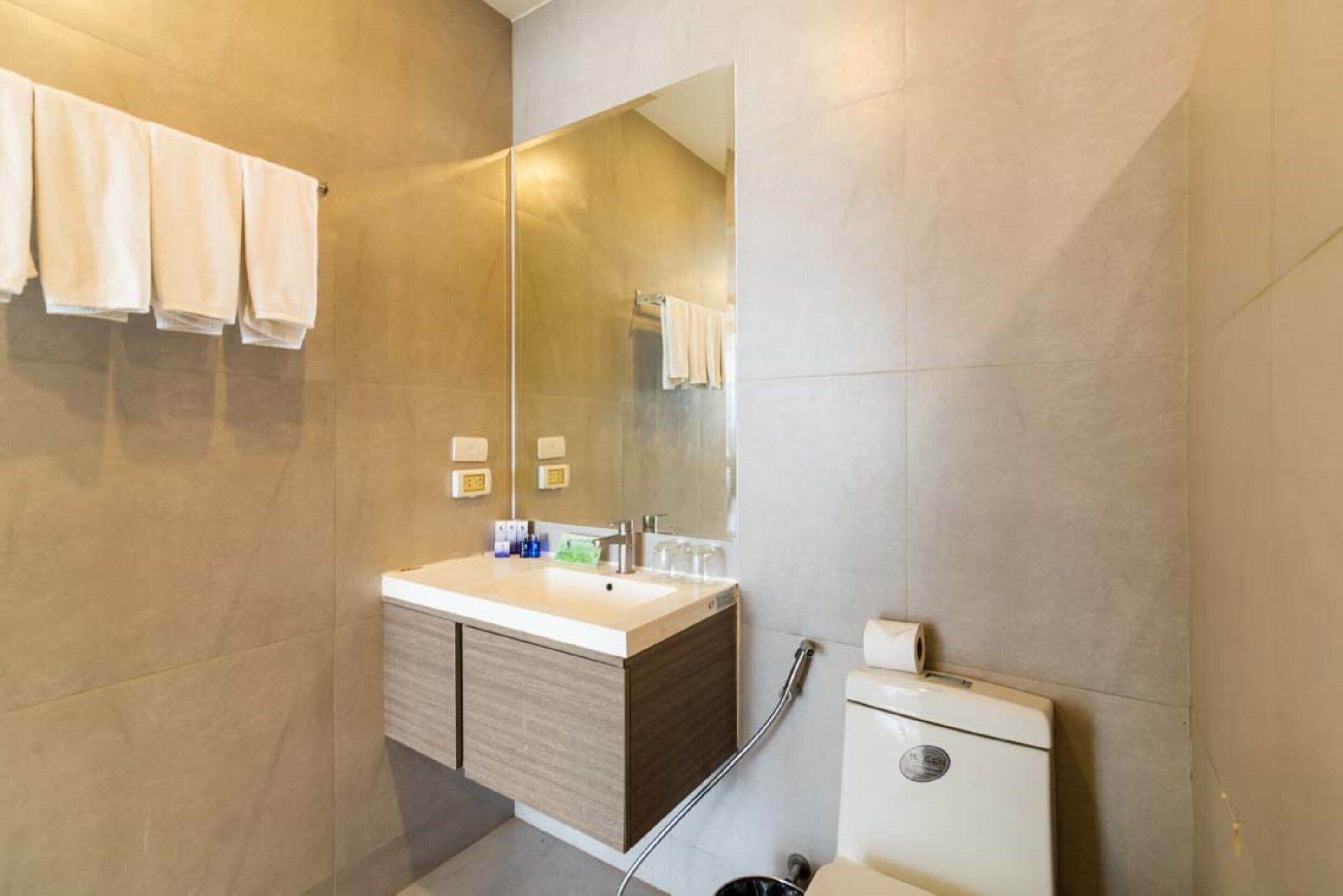Un baño moderno con un espejo grande, un lavamanos y un inodoro.