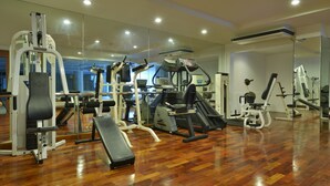 A gym with various exercise machines, a bench, and a mirrored wall. - iCheck inn Residence Sukhumvit 1 (Bangkok)