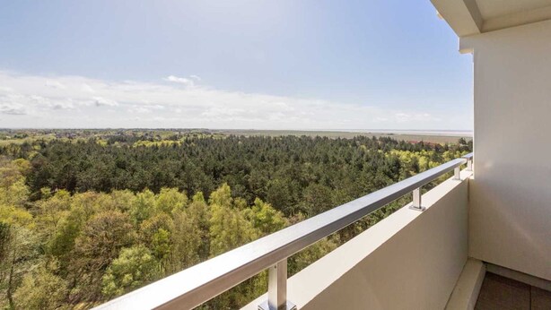 A balcony with a metal railing overlooking a forested landscape. - Apartment 178 (ID 092) - House Atlantic (Sankt Peter-Ording)
