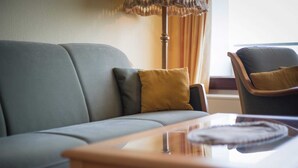 A living room with a sofa, a wooden coffee table, and a chair. - Apartment 178 (ID 092) - House Atlantic (Sankt Peter-Ording)