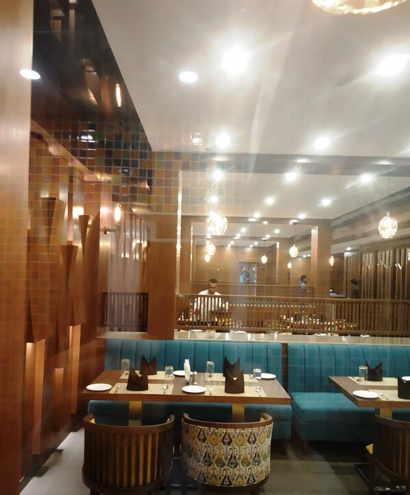 A restaurant interior with booths, tables, and hanging lights.