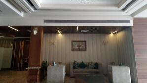 A spacious living room with a chandelier, a sofa with cushions, a coffee table, and a framed picture on the wall. - Hotel Shagun (Dera Bassi)
