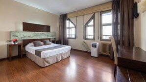 A hotel room with a large bed, a desk, a chair, a radiator, and a TV mounted on the wall. - OYO Hotel Francabel (Cuenca)