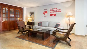 A lobby with a wooden door, a sofa, two armchairs, a coffee table, and a wall with a motivational quote. - OYO Hotel Francabel (Cuenca)