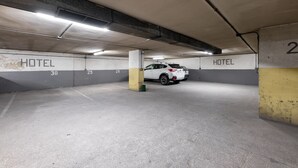 A multi-level underground parking garage with concrete walls, numbered parking spaces, and a white car parked in one of the spaces. - OYO Hotel Francabel (Cuenca)