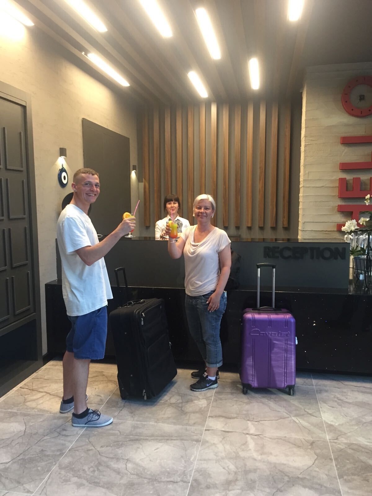A reception area with a wooden panel wall, a reception desk, and two suitcases.