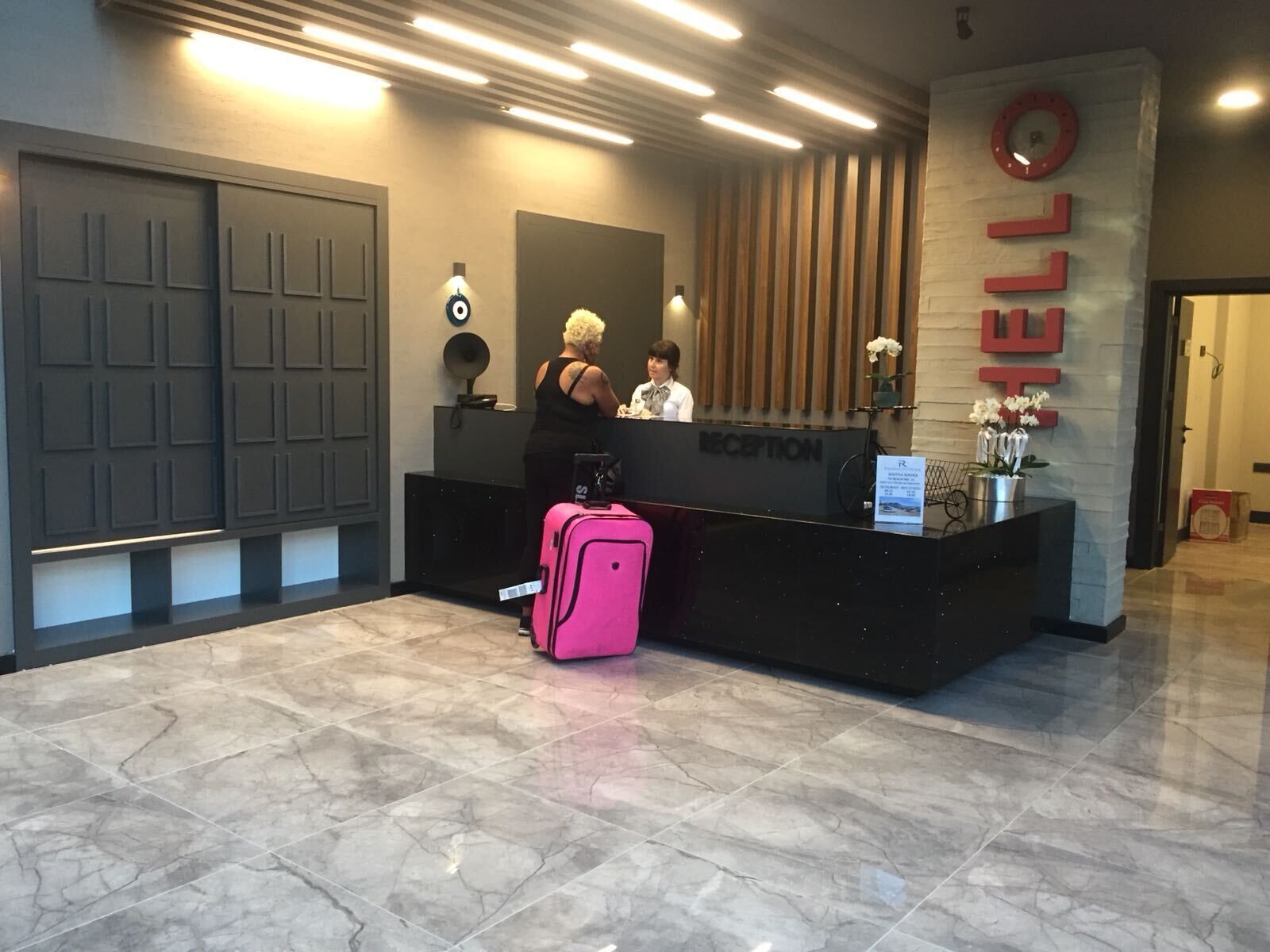 Un comptoir d’accueil avec une pancarte indiquant « BONJOUR », une horloge et un bureau d’accueil.