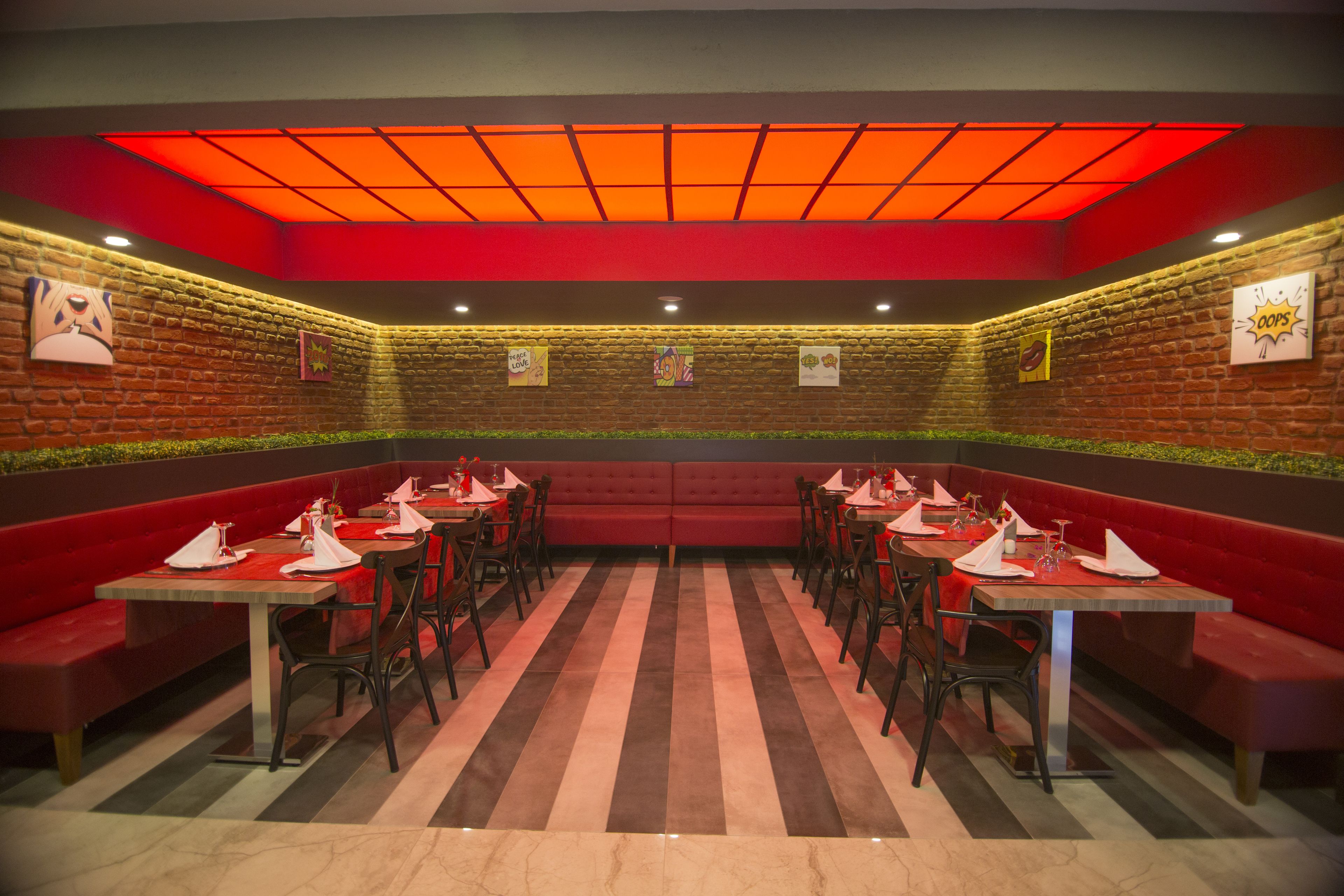 A restaurant with red booths and tables, brick walls, and a red ceiling.