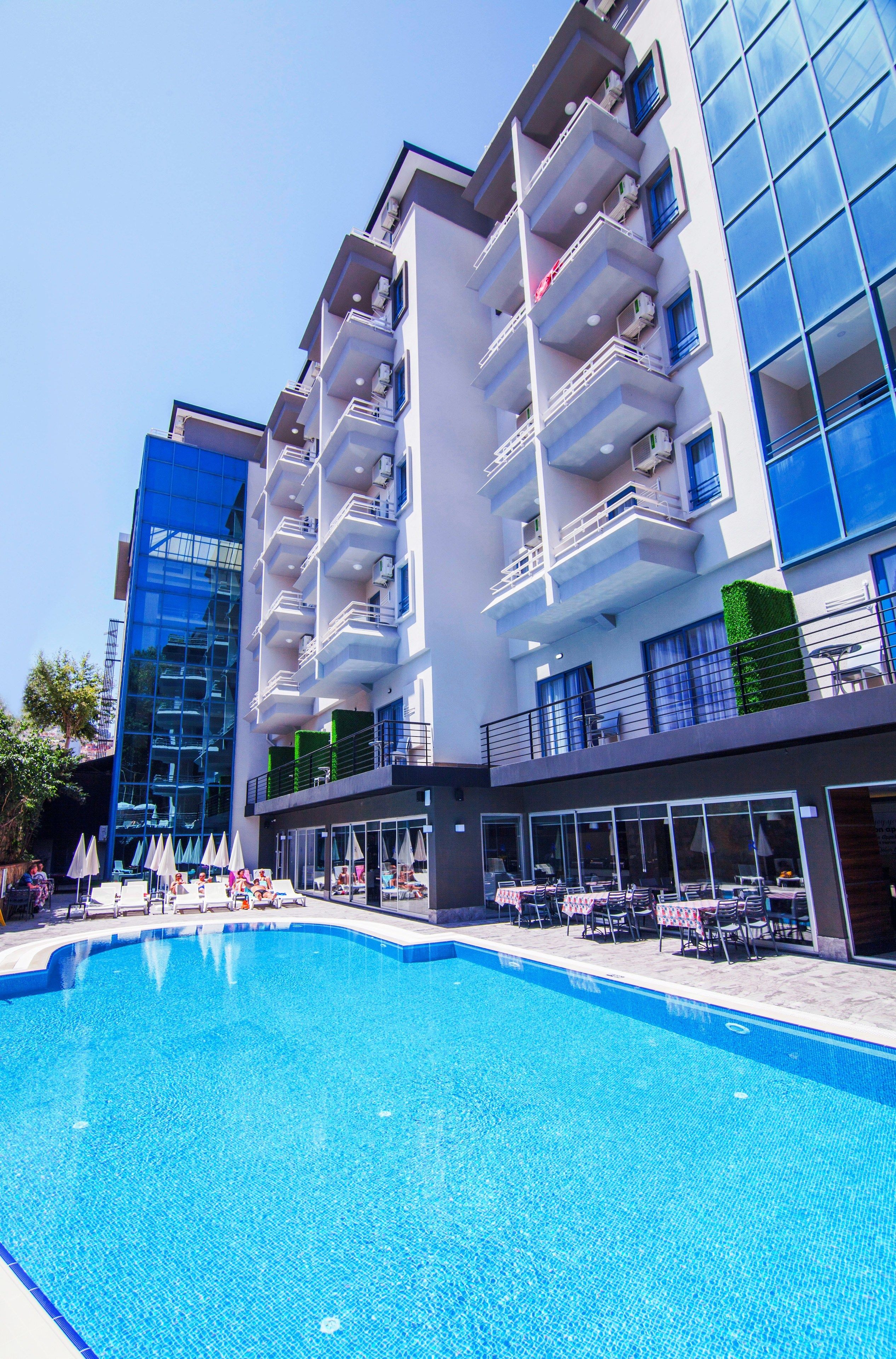 Un hôtel moderne doté d’une piscine, de nombreux balcons et d’espaces extérieurs aménagés pour se détendre.