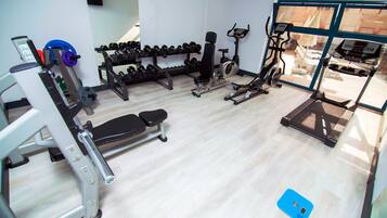 A gym with various exercise equipment, including dumbbells, a bench, and cardio machines.