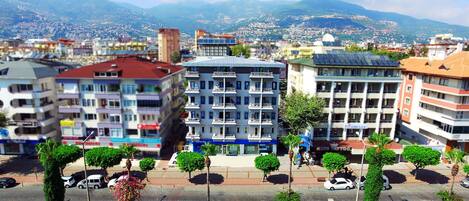 Un edificio de varios pisos con un patio central, rodeado de vegetación y vistas a un paisaje urbano con montañas al fondo.