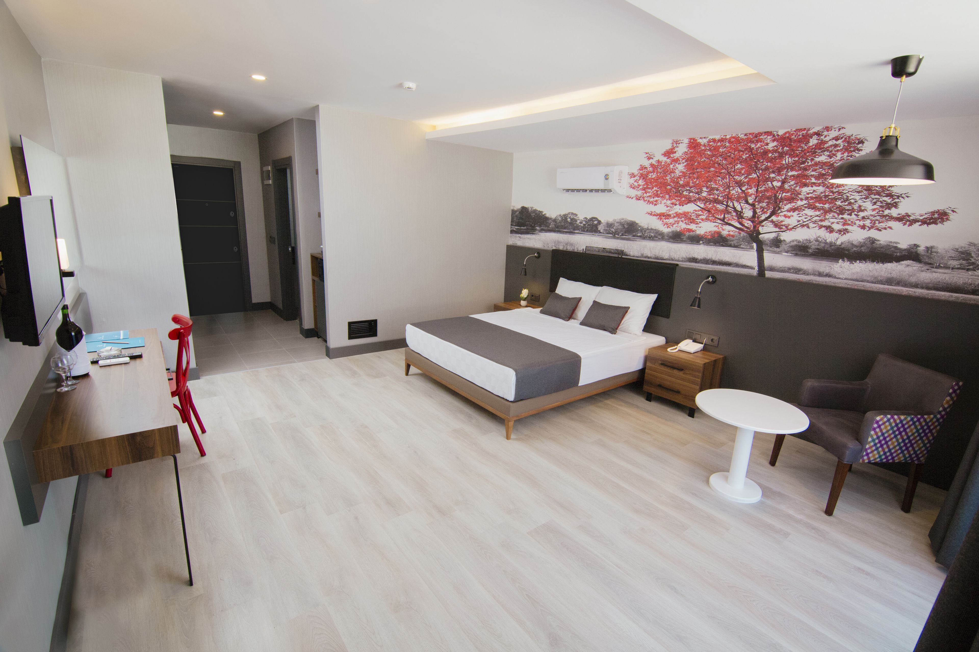 A modern hotel room with a bed, a desk, a chair, and a small table.