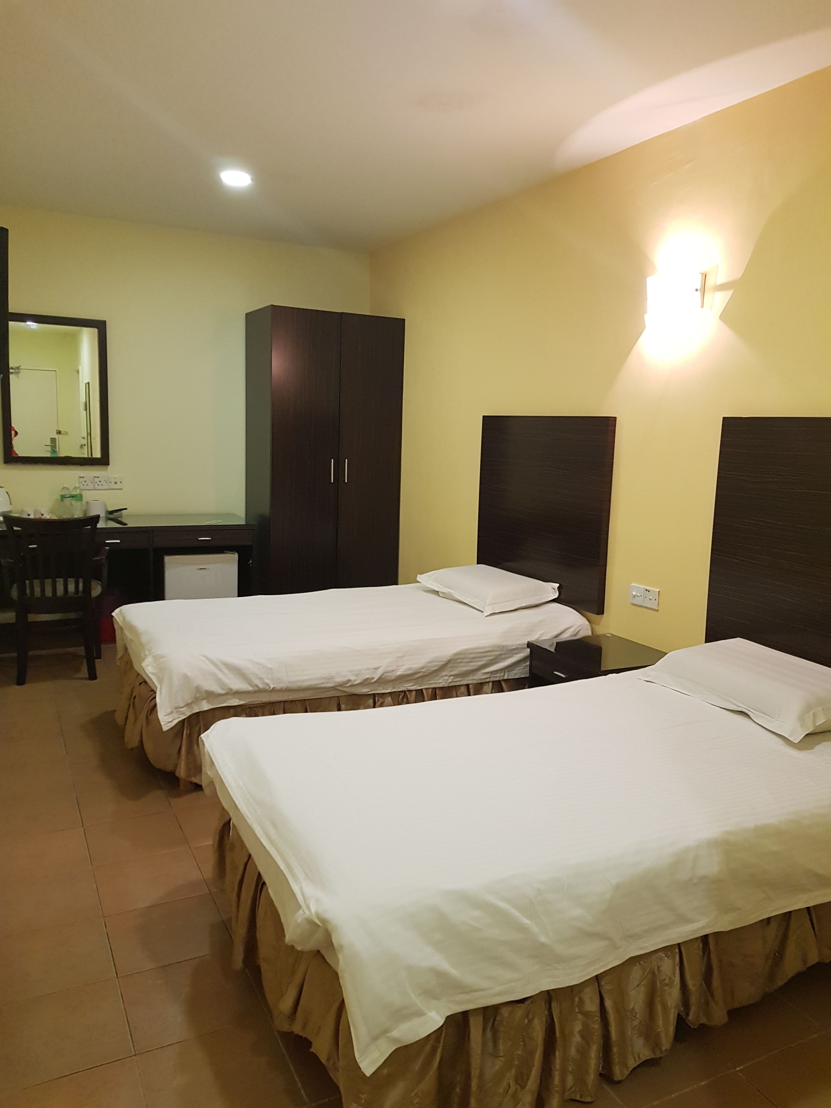 Une chambre d’hôtel avec deux lits, un bureau, une chaise et une armoire.