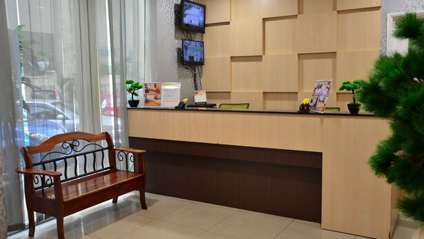 Un mostrador de recepción con un banco de madera, un televisor montado en la pared y una planta en maceta.