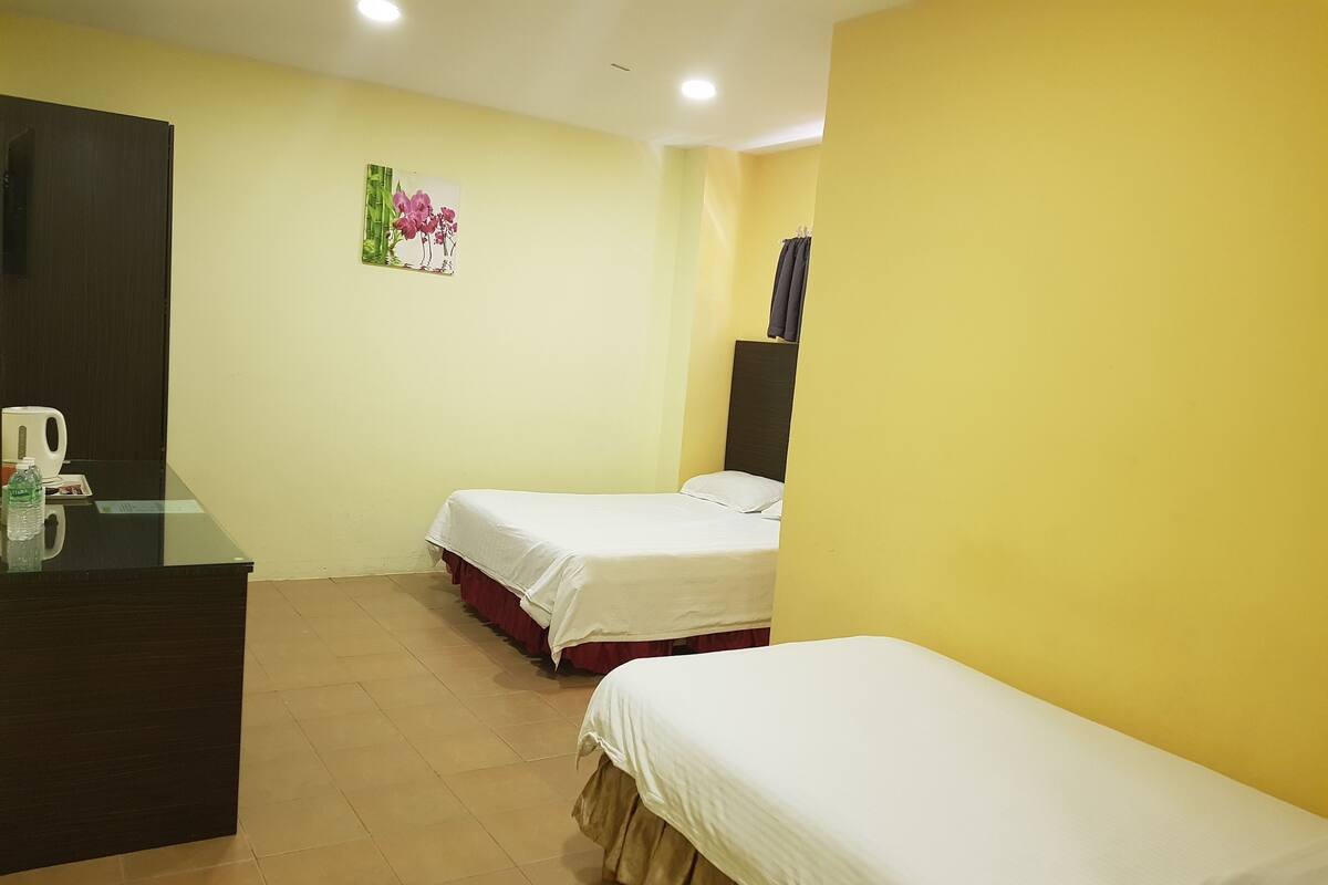 A hotel room with two single beds, a desk with a chair, a mirror, and a painting on the wall.