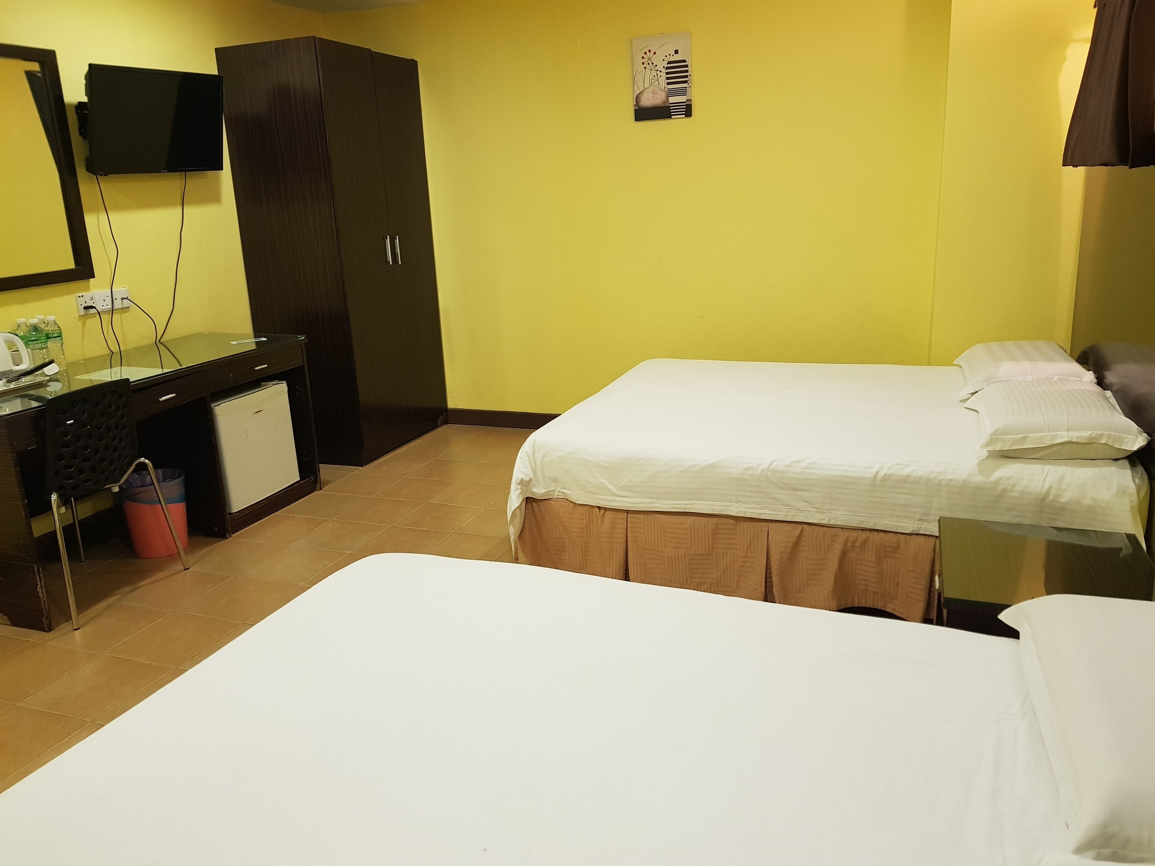 A hotel room with a bed, a desk, a wardrobe, and a television.