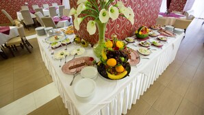 A buffet table with various dishes and a centerpiece of white flowers. - Hotel Putnik (Novi Sad)
