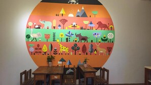 A dining area with a large, colorful mural on the wall, wooden tables and chairs, and potted plants. - 6636 B&B (Taitung)