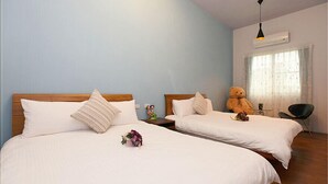 A hotel room with two beds, a large teddy bear, a small table with a vase, and a chair. - 6636 B&B (Taitung)