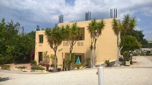 A modern building with a beige facade, multiple windows, and a gravel driveway. - Zinovia (Chania)