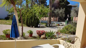 A patio with a white table and chairs, surrounded by potted plants and a blue umbrella. - Zinovia (Chania)