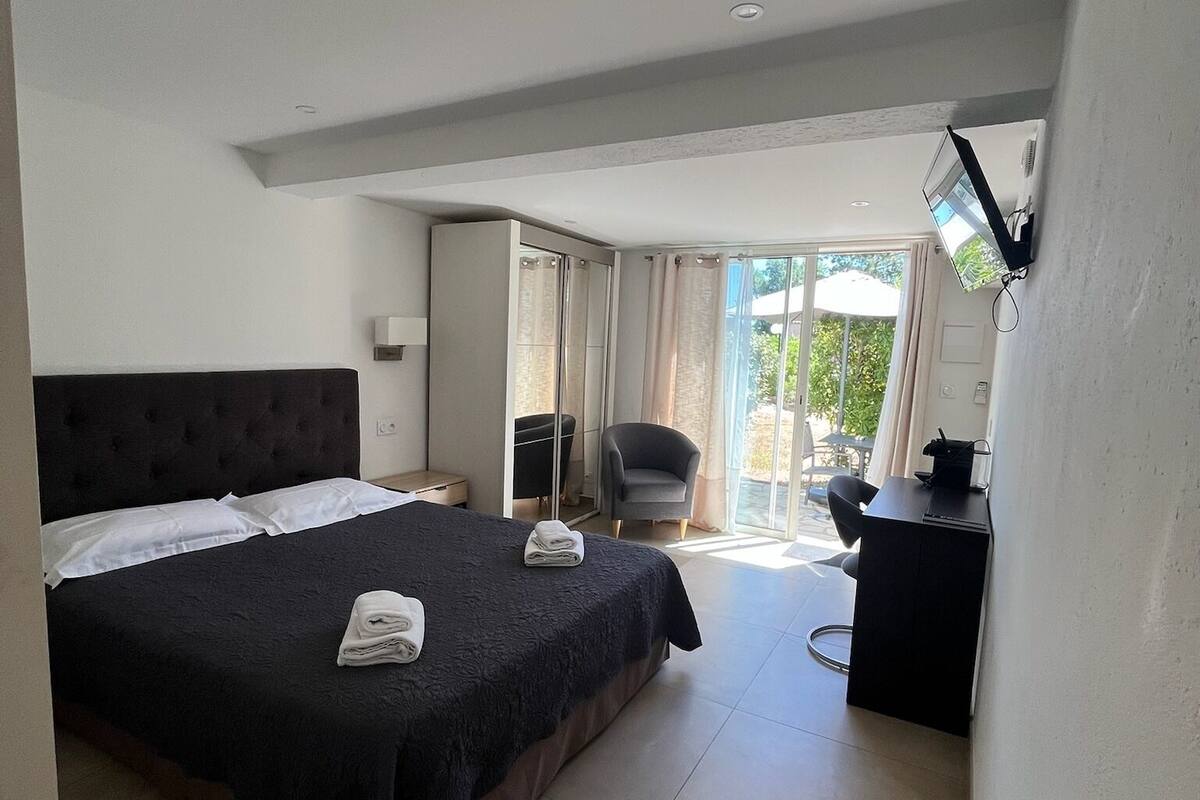 A hotel room with a large bed, a desk, a chair, and a view of the outdoors.