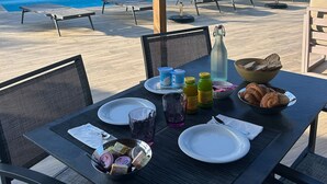 A poolside breakfast setup with a table, chairs, and a view of the pool. - Residence Les Cigales (Porto-Vecchio)