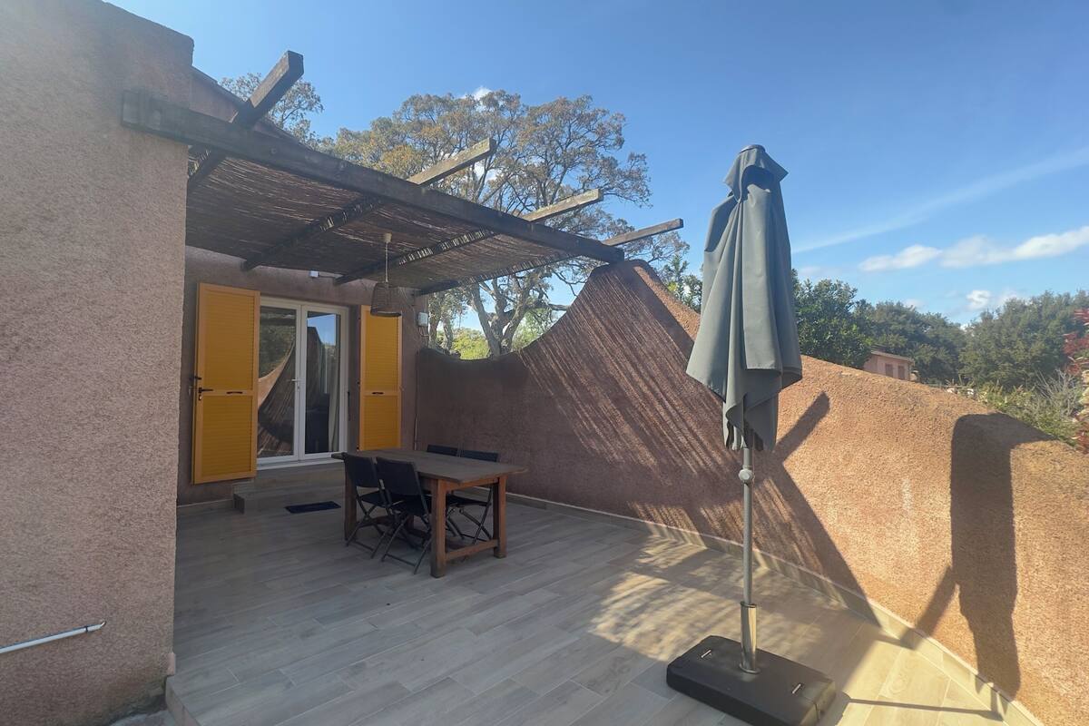 An outdoor patio area with a table and chairs, a covered seating area, and a large umbrella.