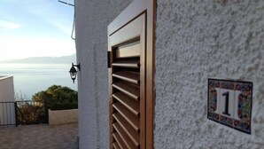 A building with a number 1 sign, a wooden door, and a view of the sea. - Vista Mare Maratea B&B (Maratea)