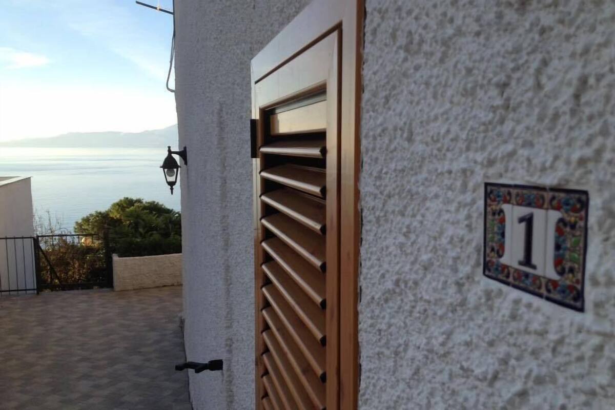 Un bâtiment portant le numéro 1, une porte en bois et une vue sur la mer.