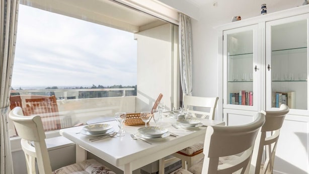 A dining area with a table set for four, chairs, a buffet basket, and a white cabinet with glass doors.