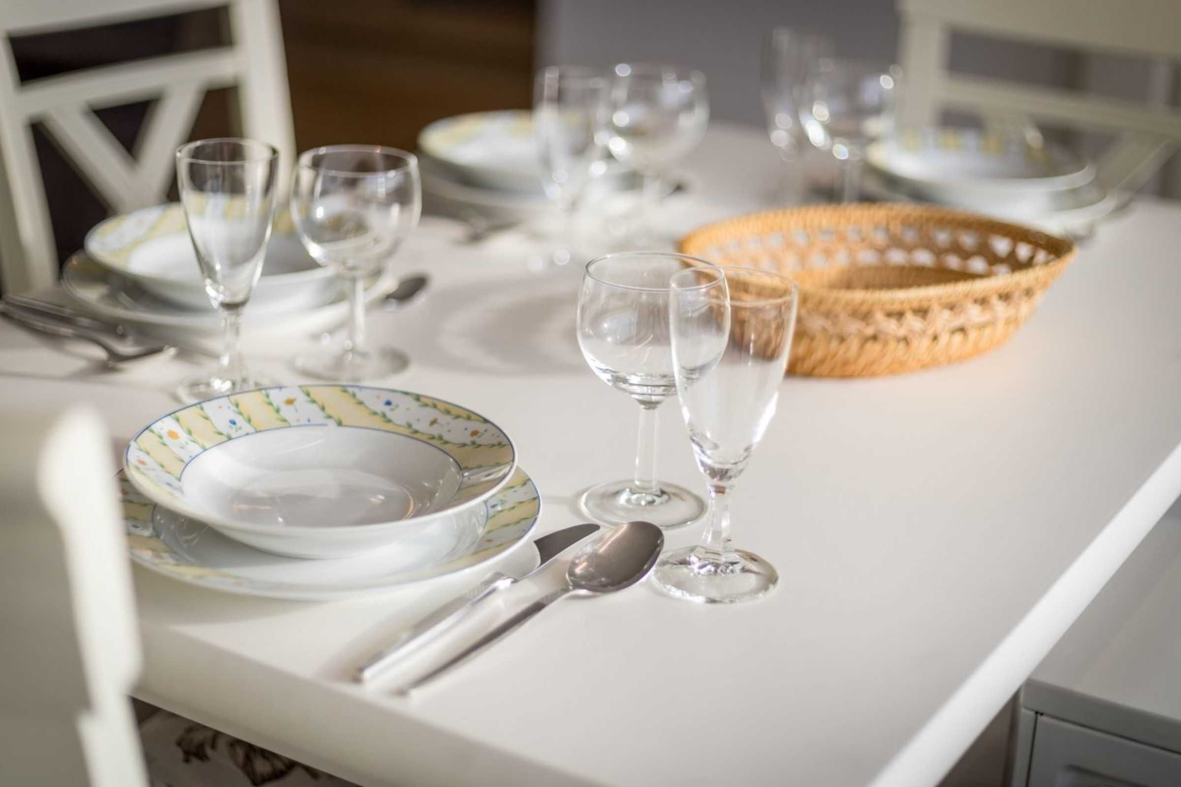 A table set with plates, cutlery, and wine glasses.