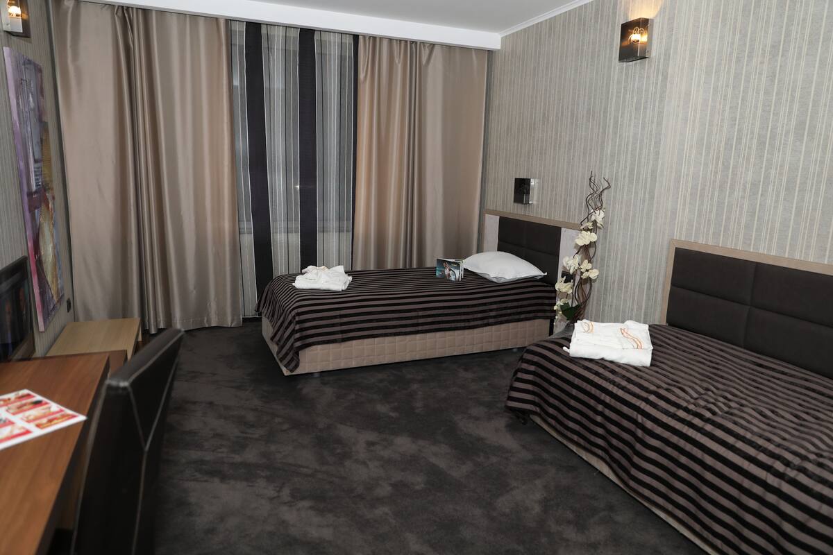A hotel room with two beds, a desk, and a chair.